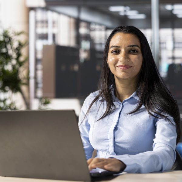 Account executive multitasking at her desk working on business goals. Female employee uses her computer for data management and project strategy, infographics analytics numbers.