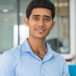 Positive Indian financial advisor holding open folder with documents and looking at camera. Smiling confident successful young businessman working in office. Business analyst concept